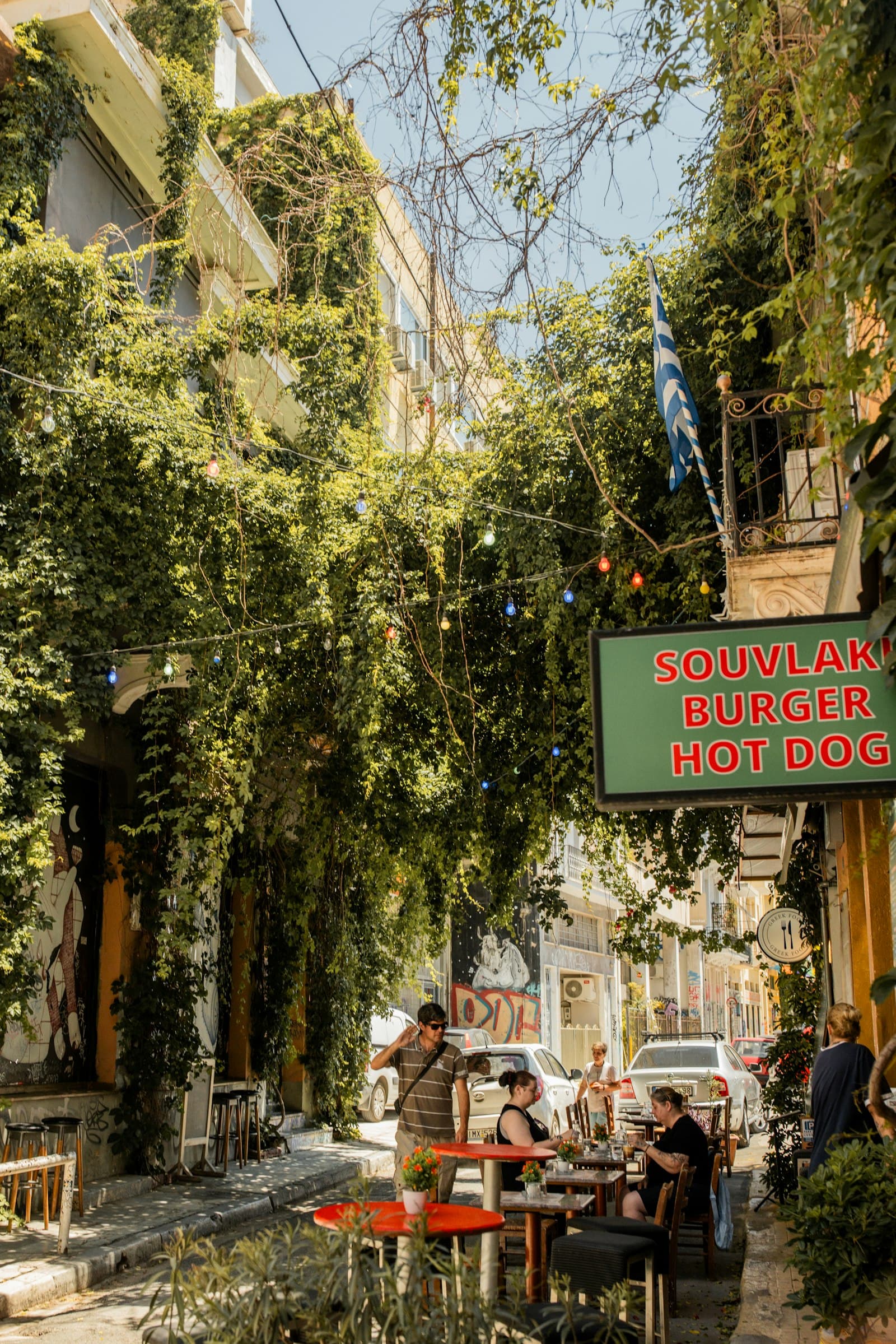 Outdoor tables on a vine-covered street strung with lights