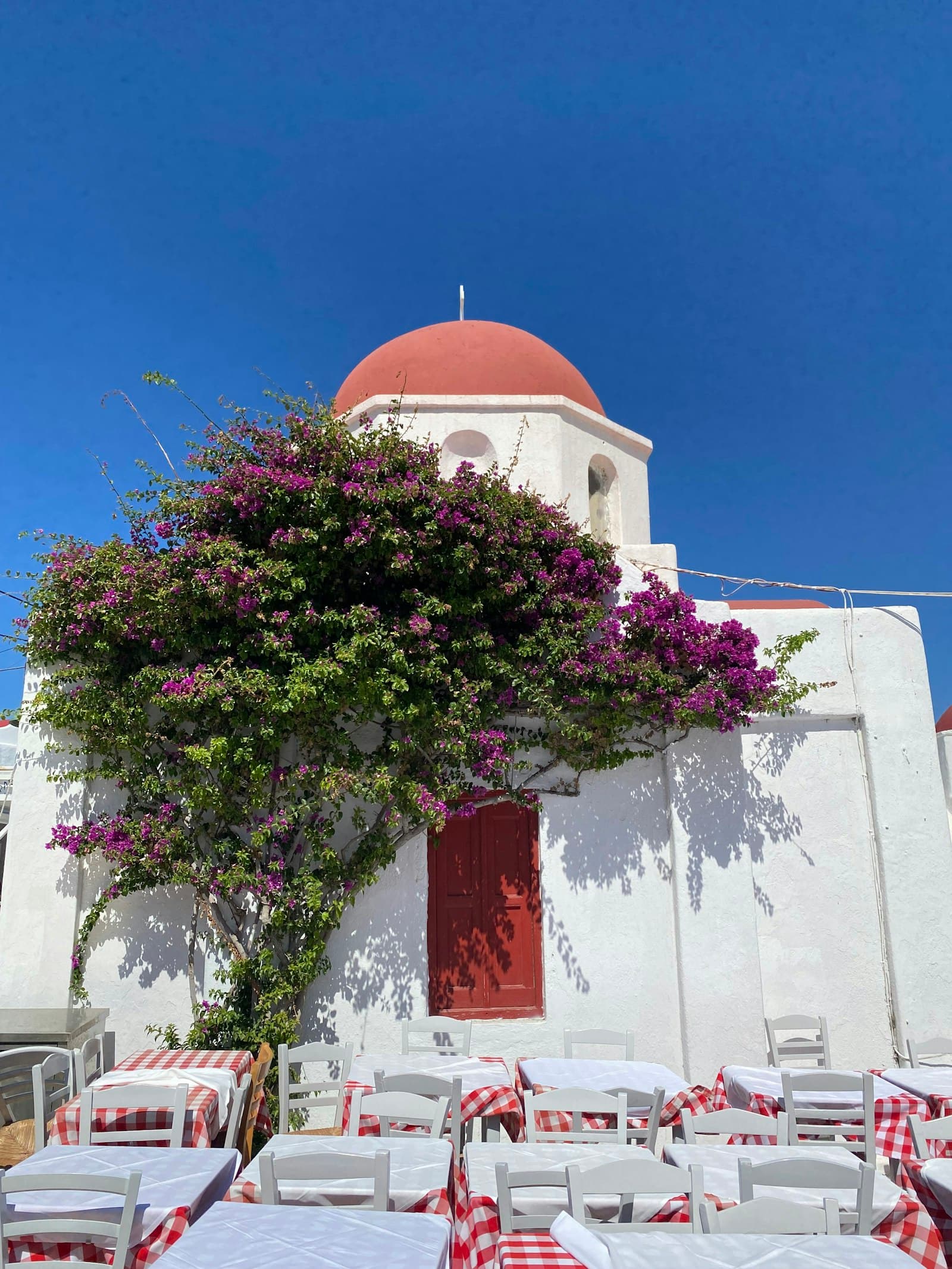Whitewashed courtyard with checked tablecloths under a bougainvillea