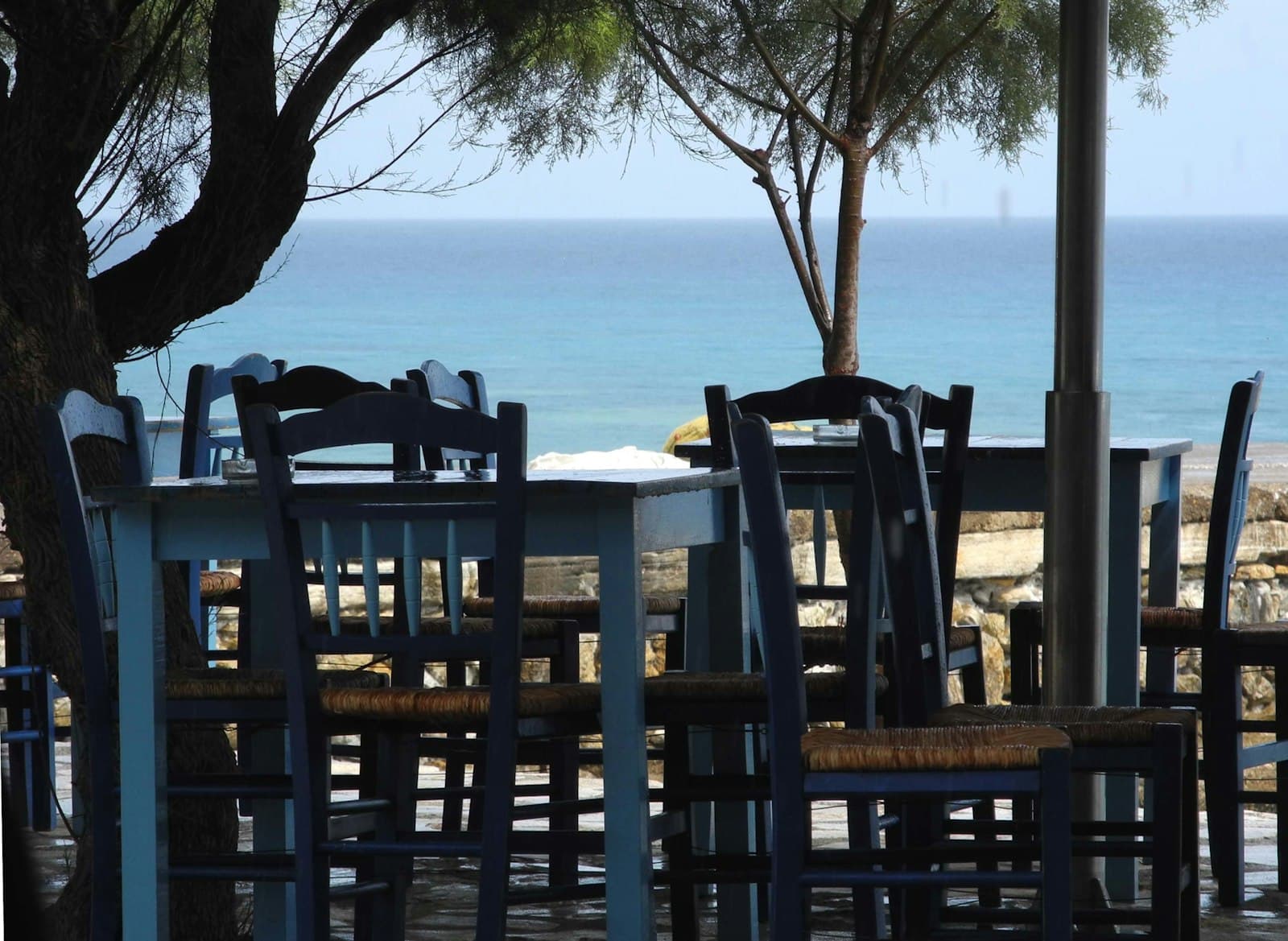 Blue taverna chairs and a table by the sea