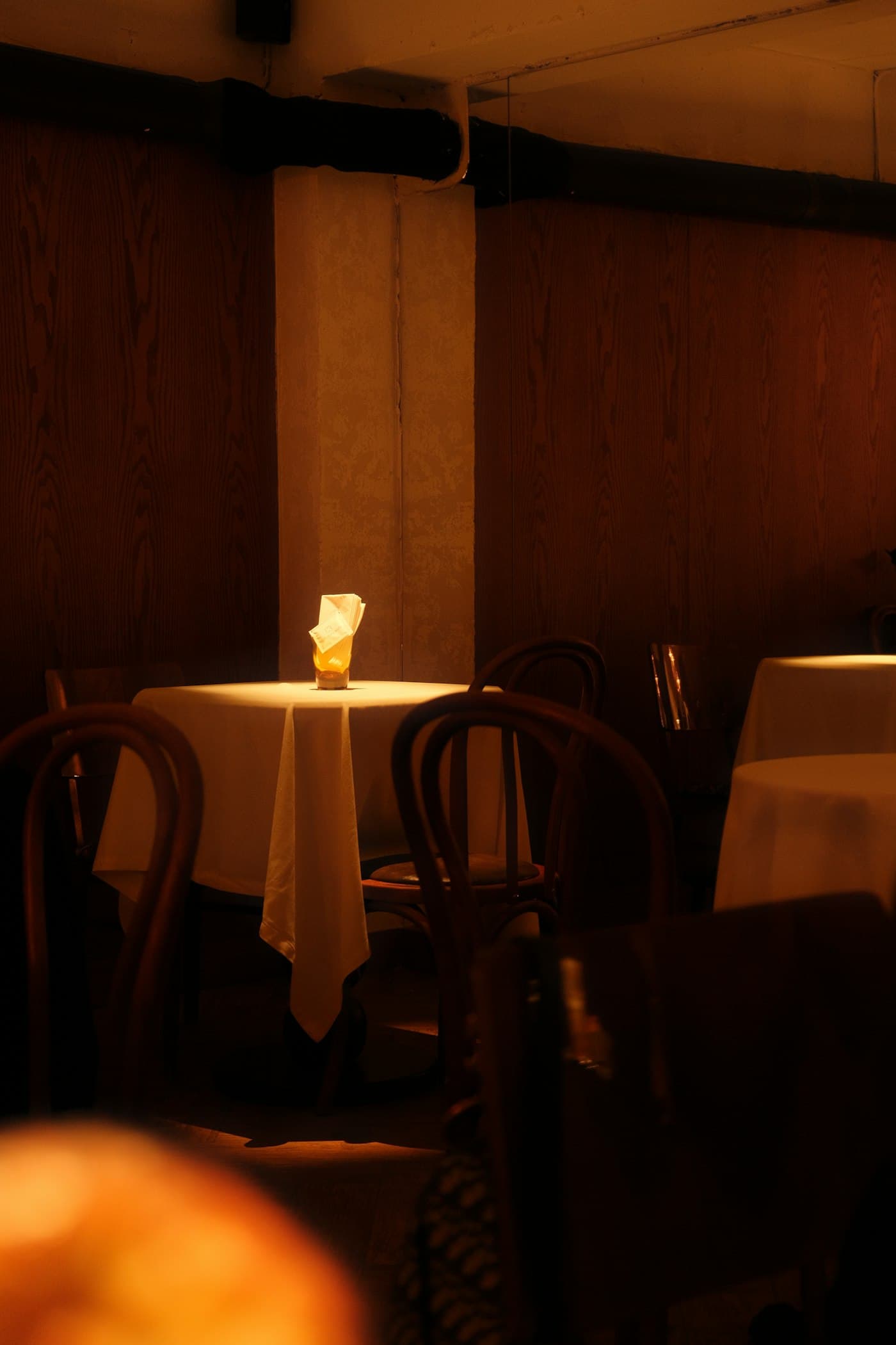 A quiet corner table set with white linen and a single lit candle