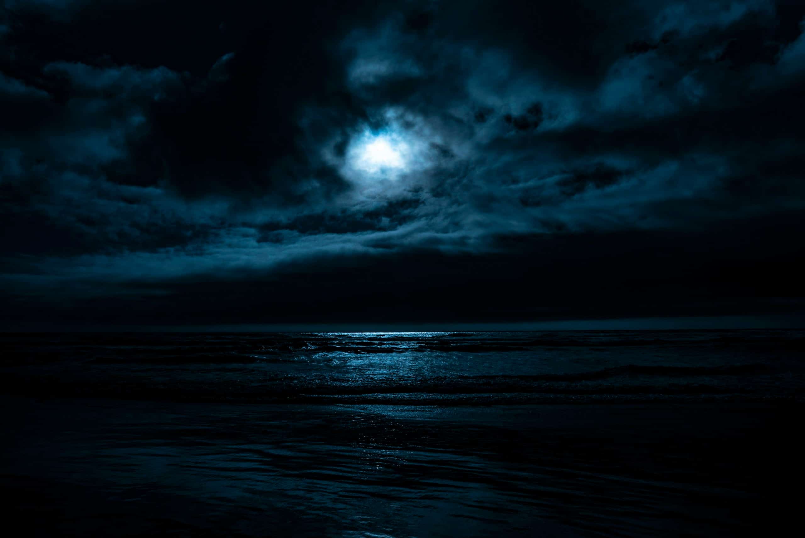 Moonlight breaking through clouds over a dark sea