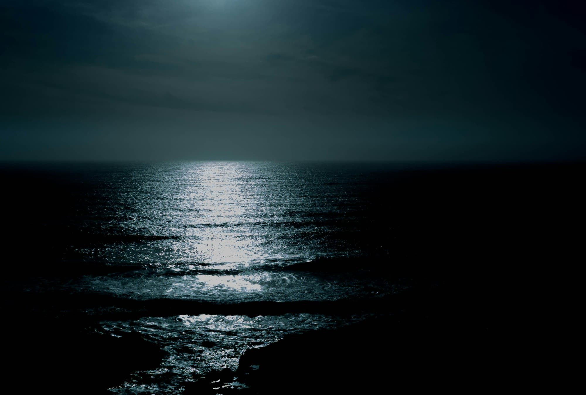 Moonlight reflected in a path across a calm dark sea